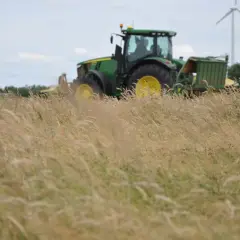 Grüner Traktor mit Anhängern im Feld, bereit für die Ernte. Die Kfz-Steuer für diesen Traktor ist ein wichtiger Faktor für Landwirte.