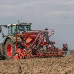 Traktor mit Sämaschine bei der Sommergerste Aussaat auf einem Feld.