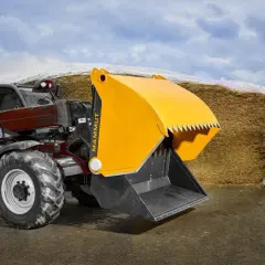Ein Teleskoplader mit gelber Schaufel steht vor einem großen Silo in der Landwirtschaft.