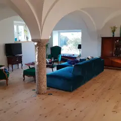 Gemütliches Wohnzimmer mit Gewölbedecke, das zeigt, wie ein alter Stall zu Wohnraum umgebaut wurde. Genehmigung für solche Projekte ist oft nötig.