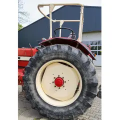 Roter Traktor mit großem Reifen und hellem Felgenhorn. Ein H-Kennzeichen ist am Traktor angebracht.