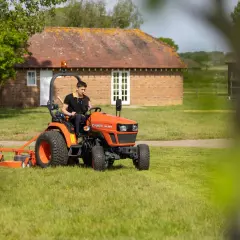 Mann fährt orangenen Kleintraktor mit Mähwerk. Welche Traktoren darf ich mit Klasse B fahren? Dieser hier ist klein genug.
