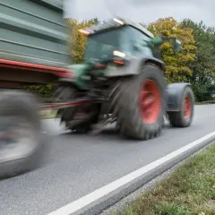 Ein Traktor mit Anhänger fährt auf einer Landstraße. Ab wann darf man Traktor fahren? Das ist eine wichtige Frage für junge Landwirte.