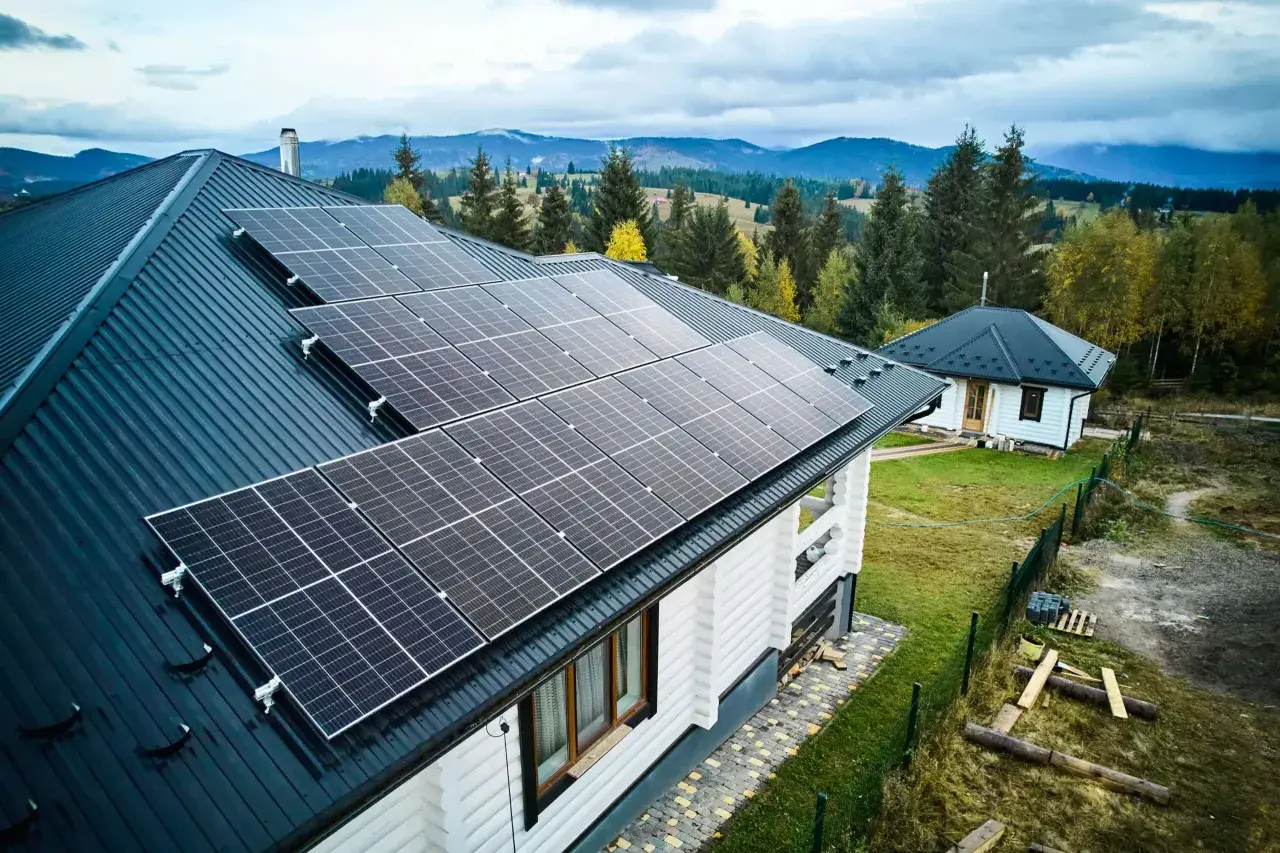 Häuser mit Solarmodulen auf dem Dach, bereit, Solarstrom zu verkaufen. Im Hintergrund bewaldete Hügel.