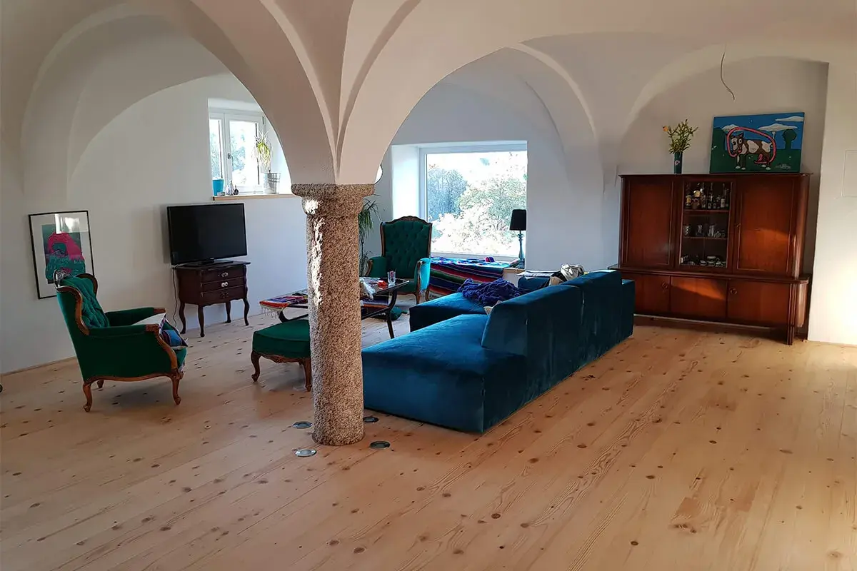 Gemütliches Wohnzimmer mit Gewölbedecke, das zeigt, wie ein alter Stall zu Wohnraum umgebaut wurde. Genehmigung für solche Projekte ist oft nötig.