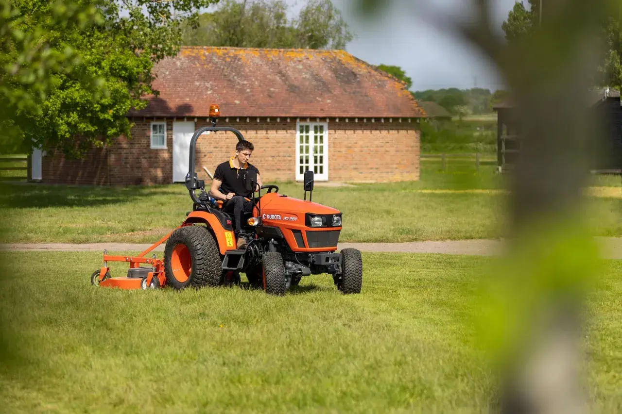 Mann fährt orangenen Kleintraktor mit Mähwerk. Welche Traktoren darf ich mit Klasse B fahren? Dieser hier ist klein genug.