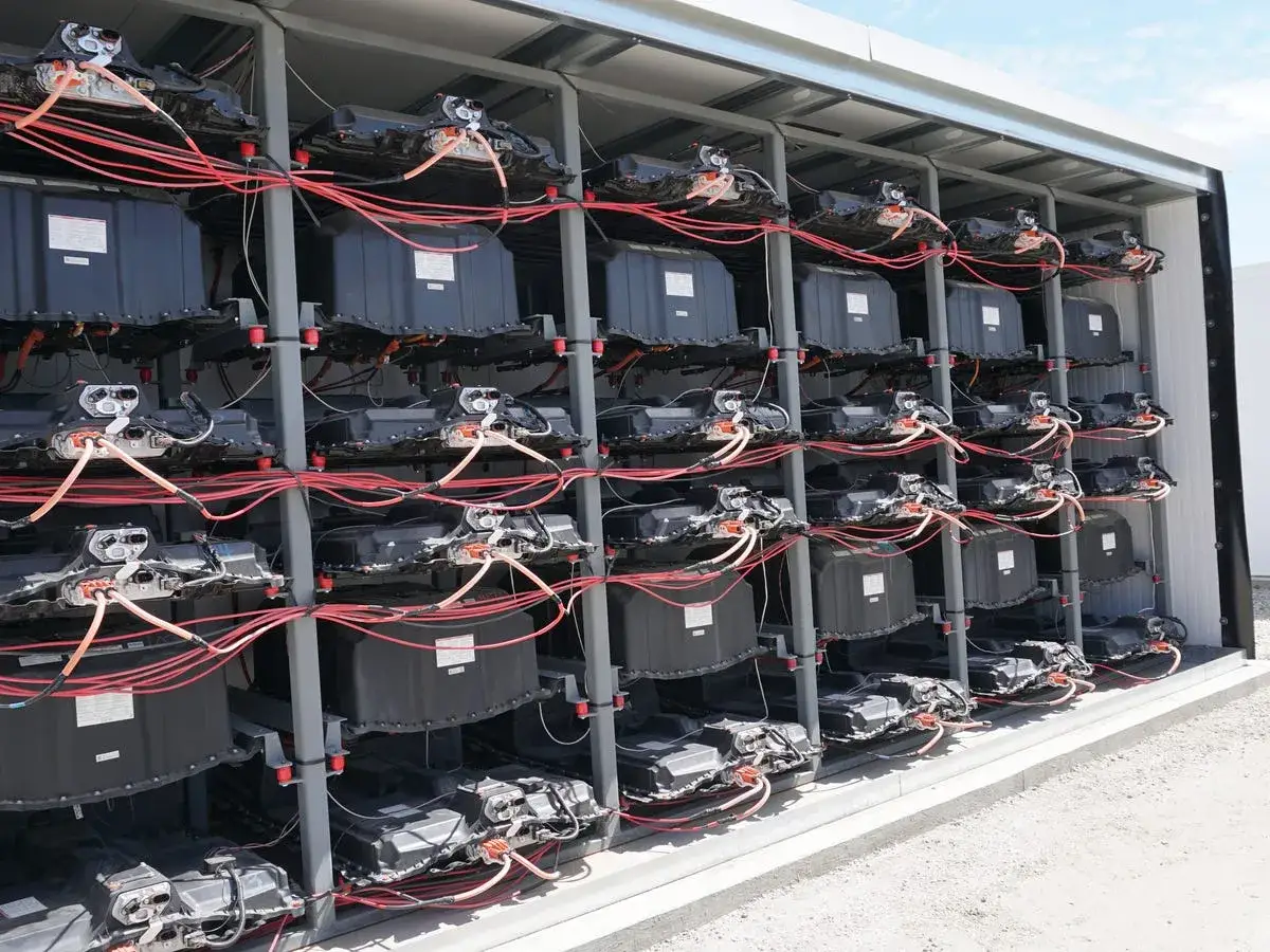 Reihen von schwarzen Batteriemodulen, verbunden mit roten Kabeln, bilden eine beeindruckende Autobatterie als Solarspeicher-Anlage.