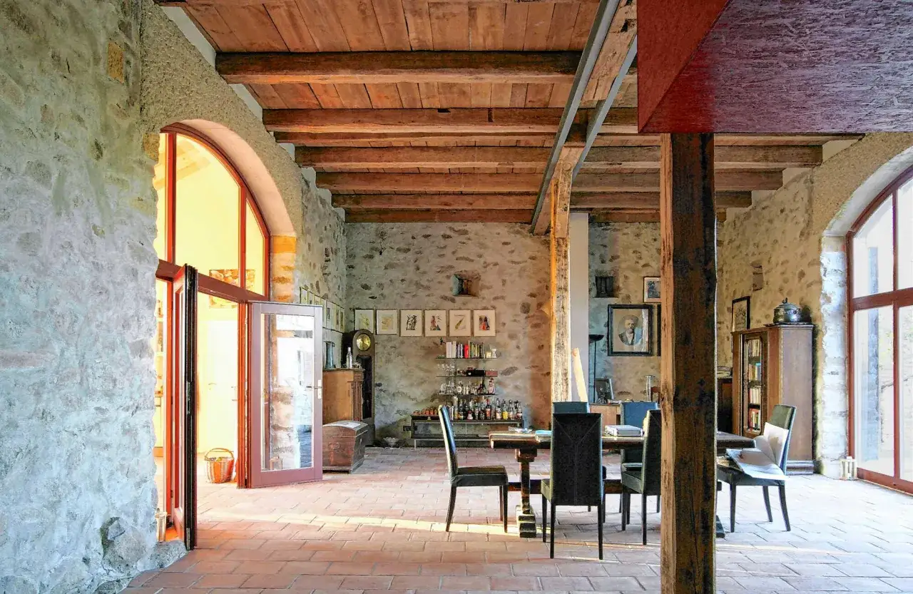 Umbau eines alten Stalls zu Wohnraum mit Genehmigung. Rustikale Steinw&auml;nde, Holzbalkendecke, Ziegelboden, Essbereich, Bar und Fenster.