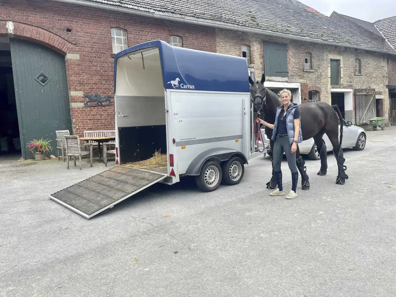 Frau mit Pferd am Anhänger, bereit für den Transport. Beachten Sie die Pferde transportieren Vorschriften für sicheres Reisen.