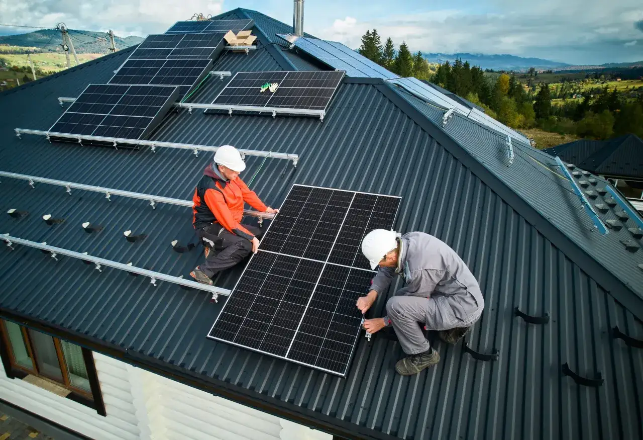 Zwei Handwerker installieren Solarmodule auf einem Dach. Die Montage ist ein wichtiger Schritt bei der Planung der kosten pv anlage.