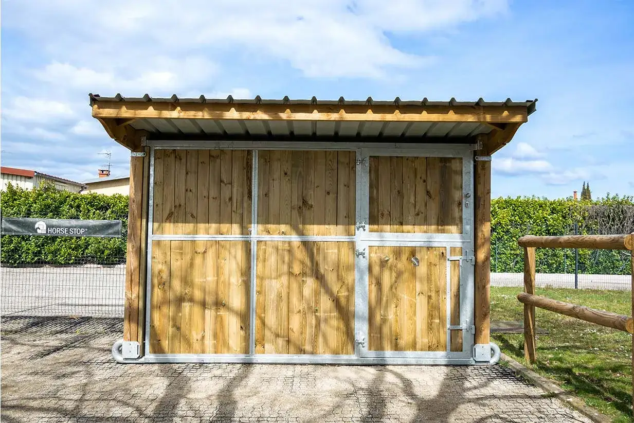 Ein mobiler Pferdestall ohne Baugenehmigung, aus Holz und Metall, mit Dach und Türen. Perfekt für flexible Pferdeunterbringung.