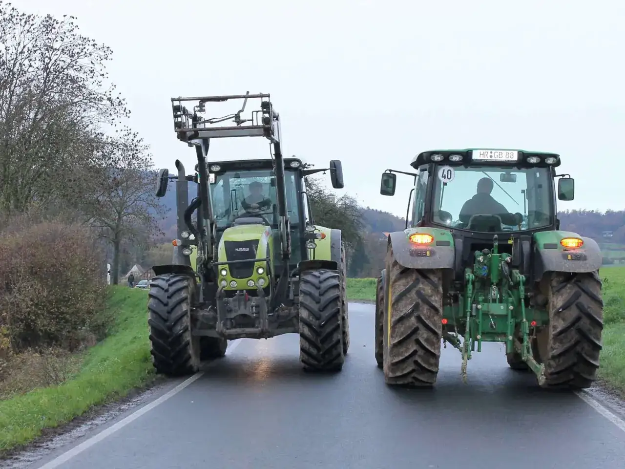 Zwei Traktoren fahren auf einer Straße, vielleicht auf dem Weg zu einer Demonstration. Sie sind bereit für den Einsatz, auch wenn es kein Traktor fahren ohne Landwirtschaft ist.